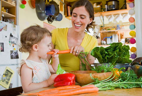 child eating carrot with parent